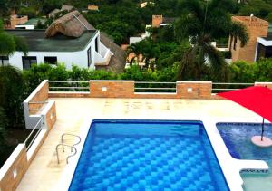 a swimming pool with a red umbrella and a house at Casa Campestre con Piscina Privada Anapoima in Girardot
