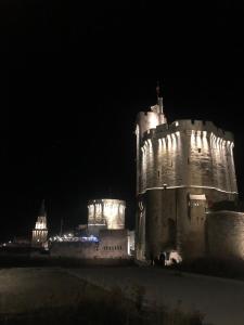 un château allumé la nuit dans l'établissement Appartements Les Rochelais, à La Rochelle