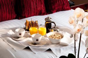 a breakfast tray on a bed with cups of coffee and orange juice at Park Central Hotel in Bournemouth