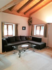 ein Wohnzimmer mit einem schwarzen Sofa und einem Glastisch in der Unterkunft City Apartment in Oberammergau