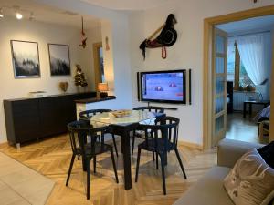 een woonkamer met een tafel en stoelen en een televisie bij Apartament Góralka in Zakopane