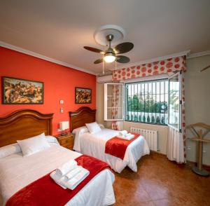 2 camas en una habitación con paredes rojas y ventana en Vivienda Turística Rural Mari Carmen, en Baeza