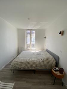 ein weißes Schlafzimmer mit einem Bett und einem Fenster in der Unterkunft Cosy Flat Carteret - Appartement centre bourg - 4 personnes in Barneville-Carteret