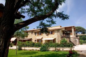 una grande casa in pietra con un albero di Agriturismo L'Antica Fattoria a Bolsena