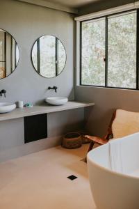 a bathroom with two sinks and two mirrors at Ocean Suites Byron Bay in Byron Bay