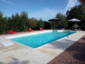 una piscina con sillas y sombrilla en Spacious vacation home with pool, en Chaumard