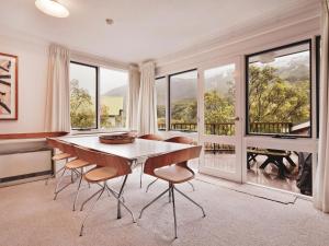 a dining room with a table and chairs and windows at Steamboat 2 bedroom with mountain view and central location in Thredbo