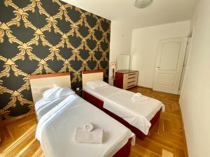 duas camas num quarto com papel de parede preto e dourado em Apartments First Line em Petrovac na Moru