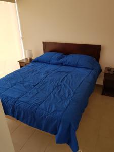 een bed met een blauw dekbed in een slaapkamer bij Apartamento con jardin a pasos del mar La Serena in La Serena