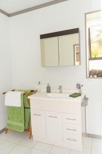 Baño blanco con lavabo y espejo en Guinea's Rest en Waipapa