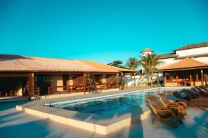 a swimming pool with chairs and a resort at Castelhana Praia Hotel - Itauna Saquarema in Saquarema
