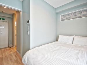 1 dormitorio con 1 cama blanca en una habitación en Tenpoint Hotel OKOU, en Naha