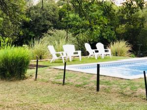 un grupo de sillas blancas junto a una piscina en Pueblo Santo, Cabañas & Suites en San Javier