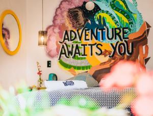 uma cama com um sinal que diz que a aventura te espera em Supertramp Hostel Cusco em Cusco