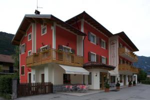 - un bâtiment rouge avec un balcon et des tables dans l'établissement Hotel Dolomiti Saone, à Tione di Trento