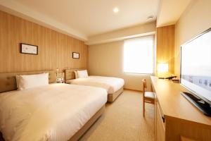 a hotel room with two beds and a television at hotel MONday Haneda Airport in Tokyo