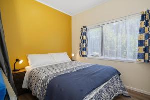 a bedroom with a bed and a window at Searenity - Waikanae Beach Holiday Home in Waikanae