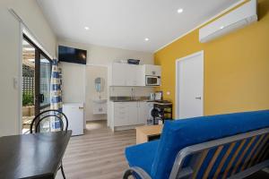 uma sala de estar com um sofá azul e uma cozinha em Searenity - Waikanae Beach Holiday Home em Waikanae