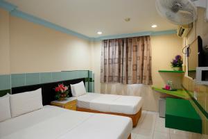 a hotel room with two beds and a tv at Cosy Inn in Miri