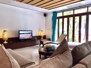 a living room with a couch and a tv at Amatapura Beachfront Villa 14, SHA Certified in Ao Nam Mao