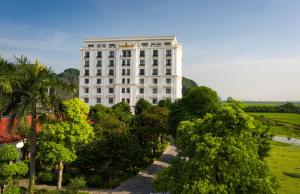 um grande edifício branco com árvores em frente em Ninh Binh Hidden Charm Hotel & Resort em Ninh Binh