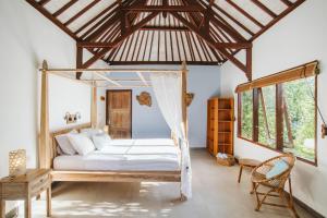 a bedroom with a bed in a room with windows at Karma Kayak in Gili Trawangan