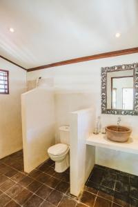 W łazience znajduje się toaleta, umywalka i lustro. w obiekcie Karma Kayak w Gili Trawangan