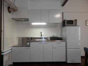 uma cozinha com armários brancos e um micro-ondas em Maple Sumikawa #201 em Sapporo