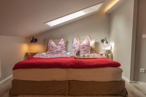 Un dormitorio con una gran cama roja con almohadas rosas y blancas en Ferienwohnung Das Lissi, en Aschau im Chiemgau