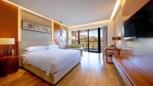 a bedroom with a large white bed and a television at Holiday Inn Nanjing Xuanwu Lake, an IHG Hotel in Nanjing