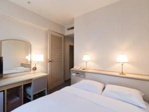 a bedroom with a bed and a desk and a mirror at Tabist Hotel Tetora Kitakyushu in Kitakyushu