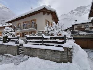 una casa cubierta de nieve frente a una casa en Taverna Larice en Valdidentro