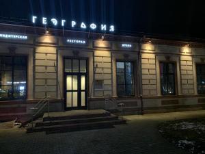 un edificio con un cartel en la parte delantera de la noche en Hotel History, en Velikiy Novgorod