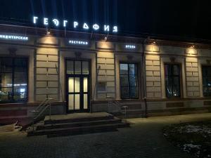 a building with a sign on the front of it at night at Hotel History in Velikiy Novgorod