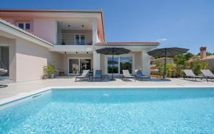 a villa with a swimming pool in front of a house at Villa Sanja in VeliGolji