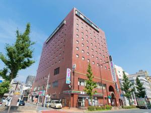 a tall red brick building on a city street at Tabist Hotel Tetora Kitakyushu in Kitakyushu