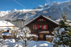 ein Haus im Schnee mit Bergen im Hintergrund in der Unterkunft Chalet Clos 66 in Chamonix-Mont-Blanc