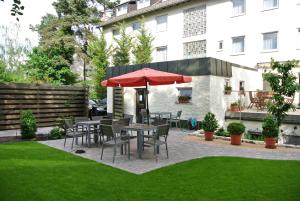 eine Terrasse mit Tischen, Stühlen und einem roten Regenschirm in der Unterkunft Nürnberger Trichter in Nürnberg