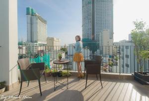 a woman standing on a balcony with a view of a city at Mojzo Inn Boutique Hotel in Nha Trang