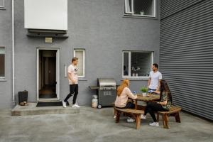 un grupo de personas sentadas alrededor de una mesa fuera de un edificio en Guesthouse Sunnuhóll en Islas Vestman