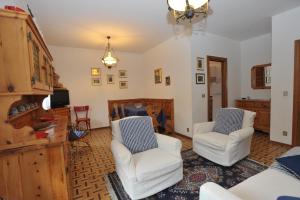 a living room with two white chairs and a tv at Baita Diana in Bormio