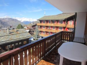 un balcone con un tavolo e una vista su un edificio di Appartement in 1700m mit Traumblick a Grächen