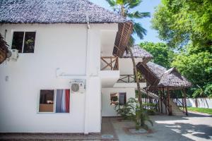 a white house with a thatched roof at Sheratton Beach Villagio in Mombasa