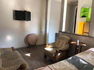 een kamer met een bed, een stoel en een tv bij Our house in Borjomi