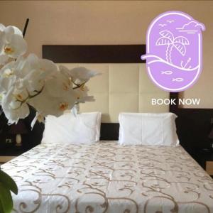ein Schlafzimmer mit einem Bett mit weißer Bettwäsche und Blumen in der Unterkunft Hotel De La Ville Relais in Fiumicino