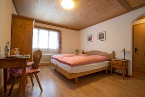 Schlafzimmer mit einem Bett, einem Schreibtisch und einem Fenster in der Unterkunft Hotel Bären in Gsteig