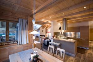 a kitchen and living room with wooden ceilings and a table at Chalet Corvara in Corvara in Badia