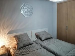 a bedroom with two beds and a clock on the wall at Prestigia Marrakech Village Appartment in Marrakesh