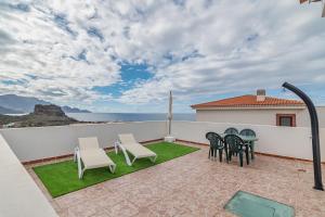 a patio with chairs and a table and a view of the ocean at Adosado El Perenquen in Agaete