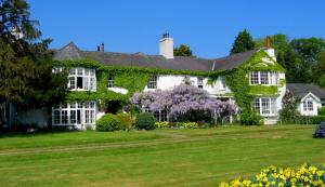 a house covered in ivy on a lawn at Glyn Isa Country House B&B and self catering Lodge in Conwy